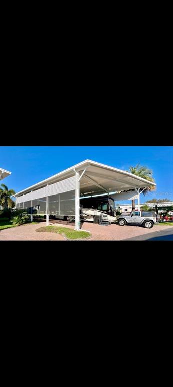 A large metal RV carport covers a motorhome and a parked SUV on a paved lot — 2504 ST GEORGE DRIVE, DAVENPORT, FL