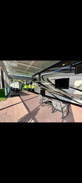 A paved patio with a covered roof sits beside a large recreational vehicle and chairs — 2504 ST GEORGE DRIVE, DAVENPORT, FL