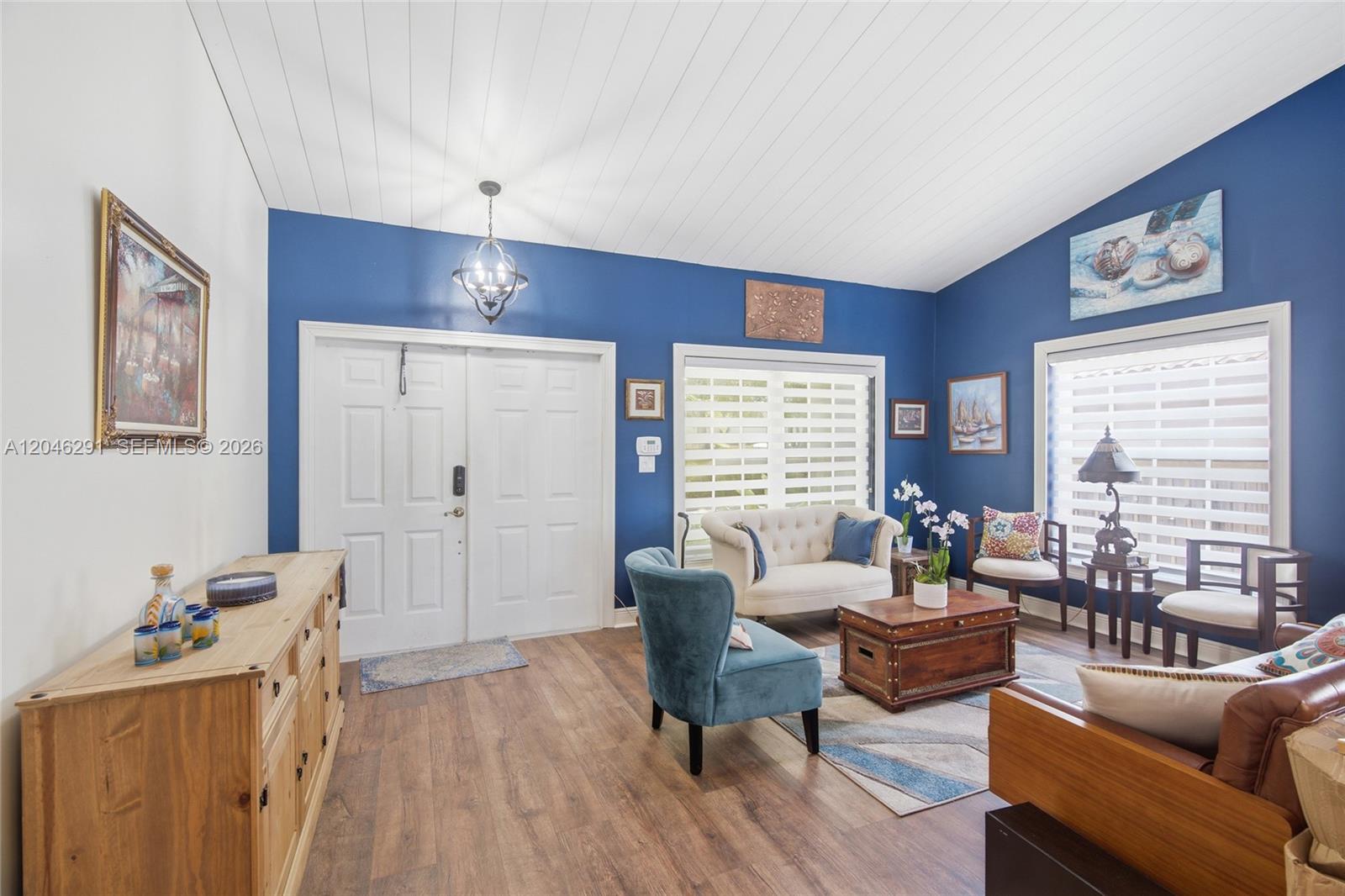 A living room features blue walls, wood-look flooring, a vaulted ceiling, and white double doors — 14110 SW 122nd Ct, Miami FL 33186, MIAMI, FL