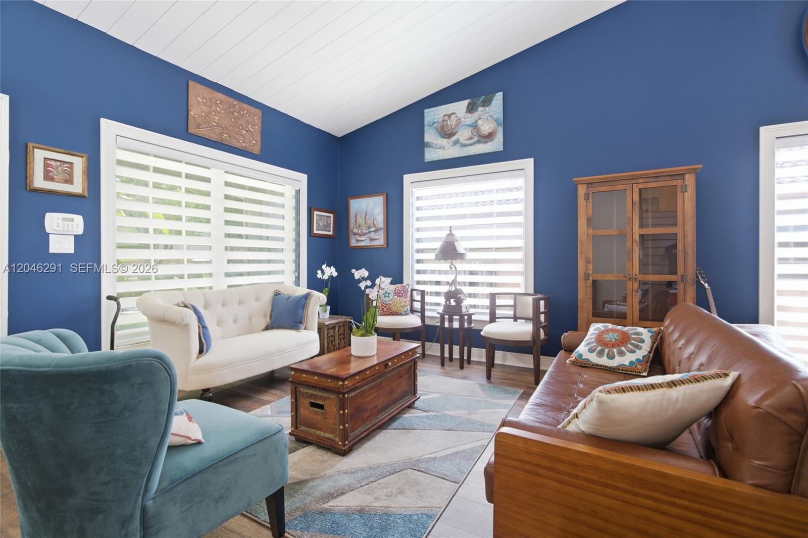 A living room features blue walls, a vaulted ceiling, and a mix of seating furniture — 14110 SW 122nd Ct, Miami FL 33186, MIAMI, FL