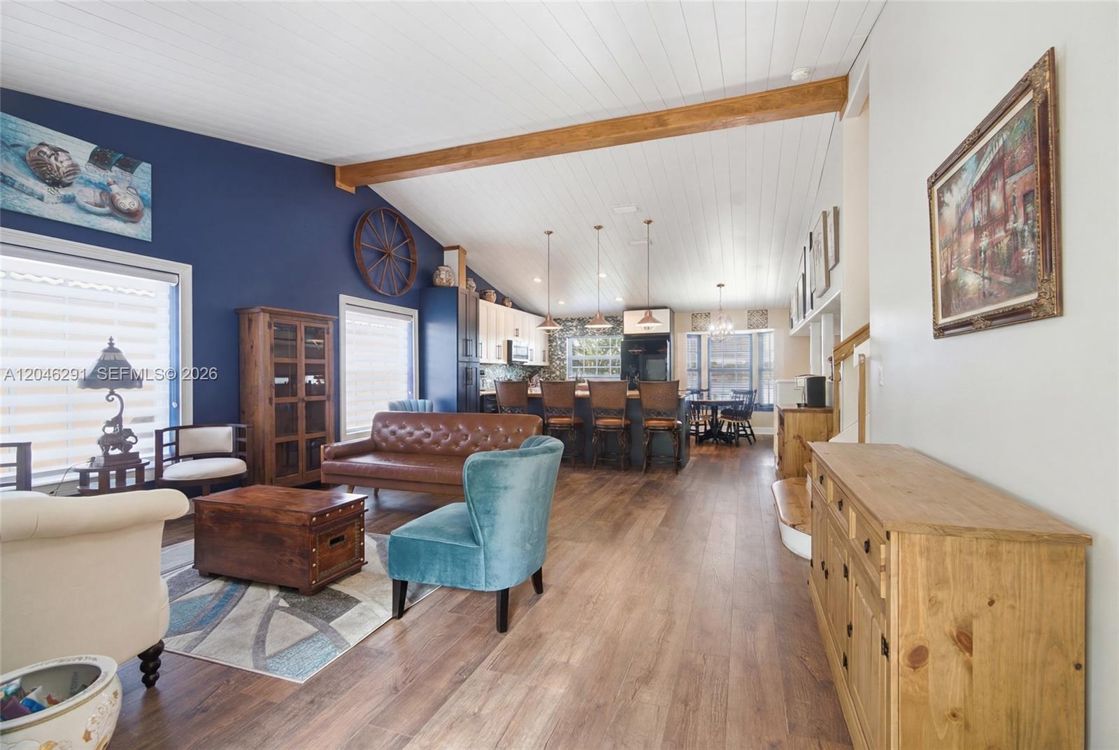This open-concept living room and kitchen features a vaulted ceiling, wood flooring, and blue walls — 14110 SW 122nd Ct, Miami FL 33186, MIAMI, FL