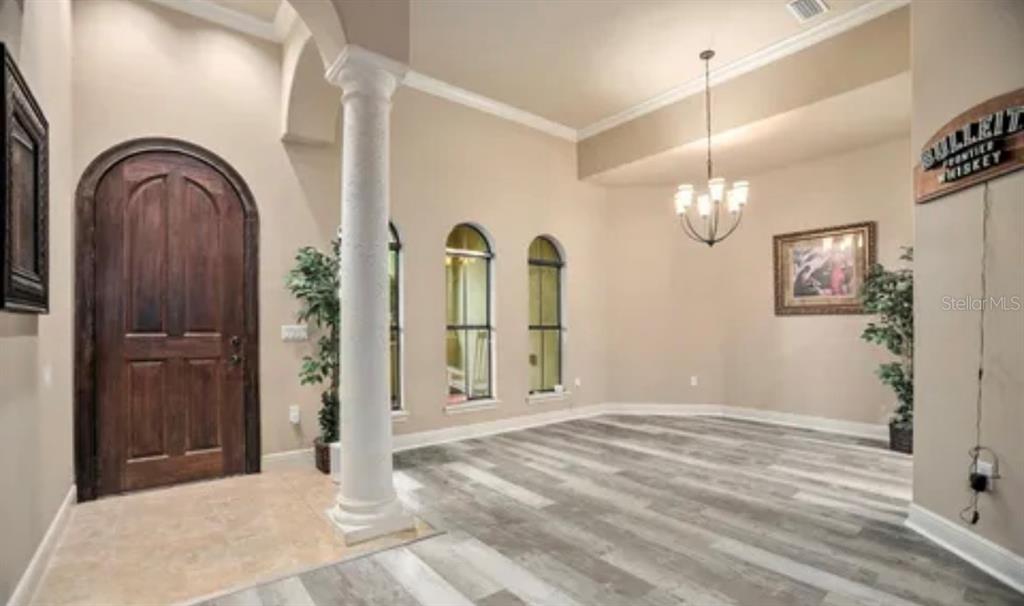 An entryway with a wooden arched door, a white column, and gray wood-look flooring — 100 VIA ROSA COURT, DEBARY, FL