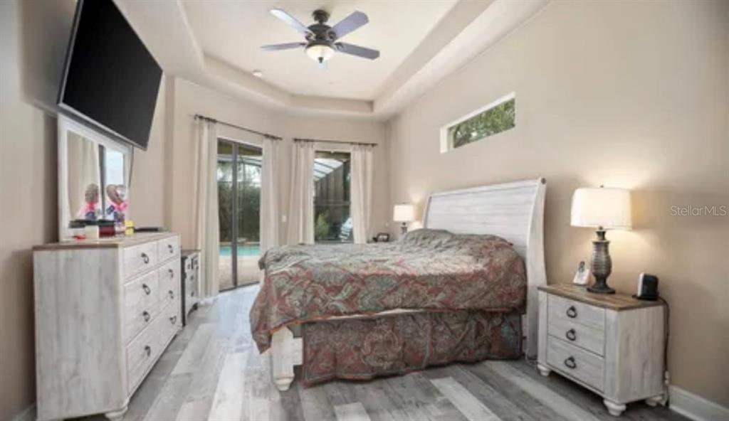 A bedroom features a white wooden bed frame, matching dresser, nightstand, and a ceiling fan — 100 VIA ROSA COURT, DEBARY, FL