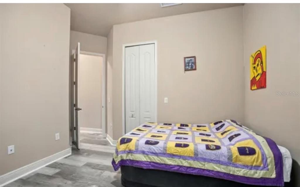 A bedroom with light walls, wood-look flooring, a closet, and a bed with a quilt — 100 VIA ROSA COURT, DEBARY, FL