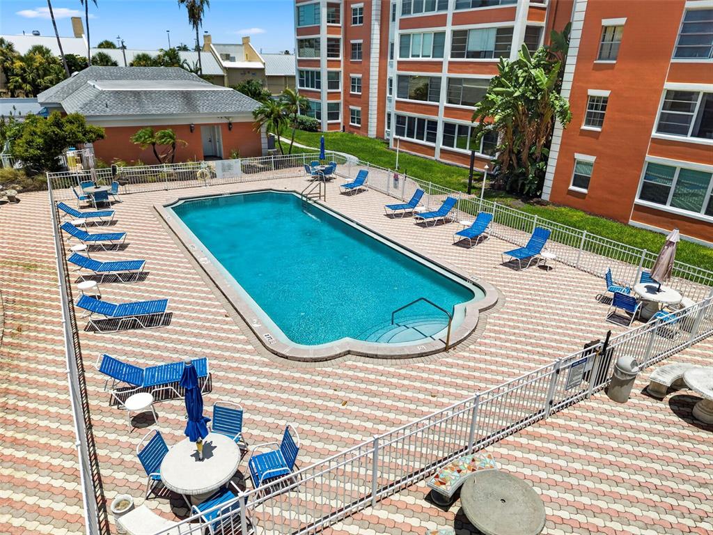 An outdoor swimming pool surrounded by lounge chairs and tables on a paved deck — 6960 20TH AVENUE N UNIT 105, ST PETERSBURG, FL