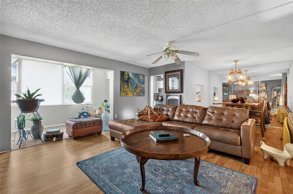 A living room features a brown leather sectional, a round wooden coffee table, and wood flooring — 6960 20TH AVENUE N UNIT 105, ST PETERSBURG, FL