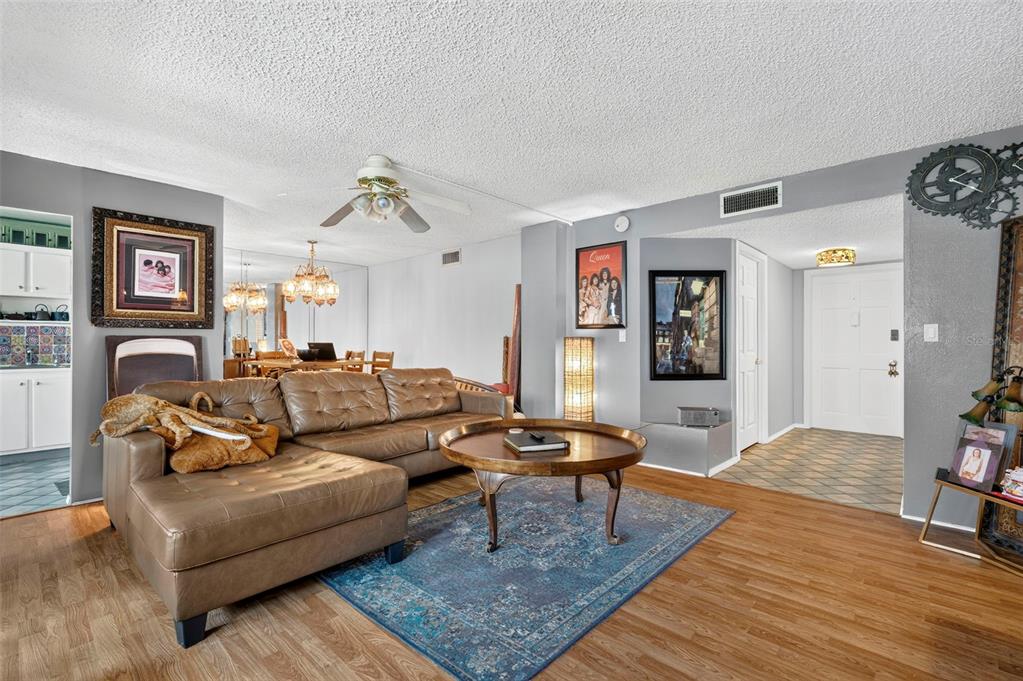 A living room features a brown leather sectional, a round coffee table, and wood flooring — 6960 20TH AVENUE N UNIT 105, ST PETERSBURG, FL