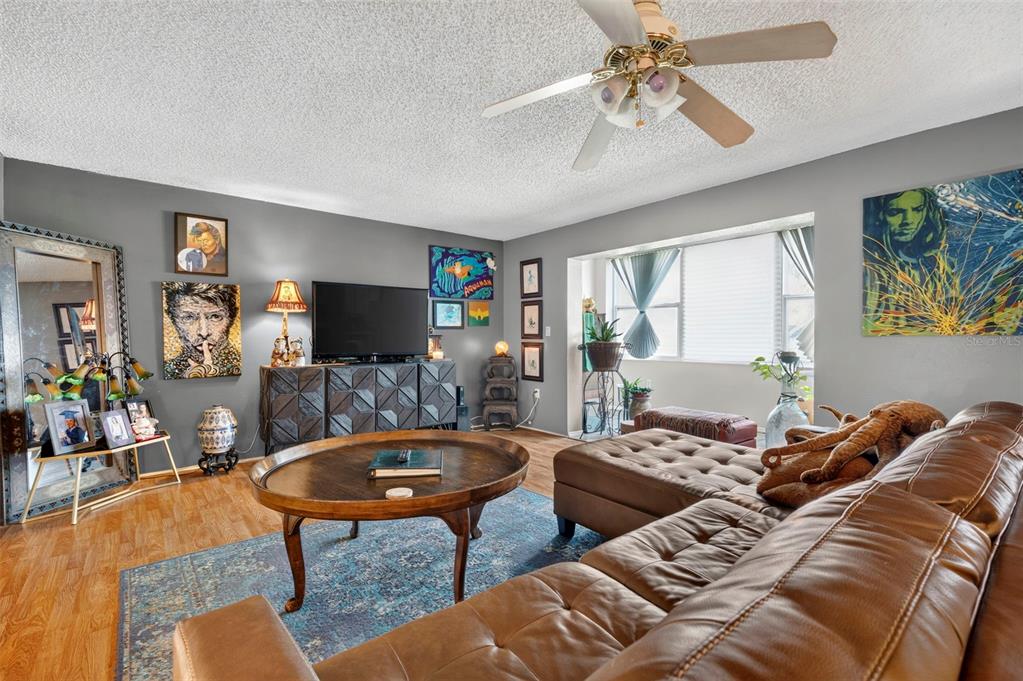 A living room features a brown leather sectional, a wooden coffee table, and gray walls — 6960 20TH AVENUE N UNIT 105, ST PETERSBURG, FL