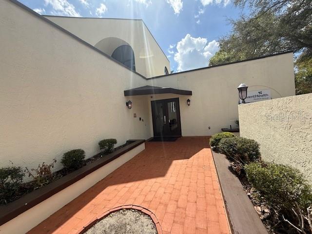 A brick walkway leads to the entrance of a beige building with a dark awning — 610 JASMINE ROAD, ALTAMONTE SPRINGS, FL