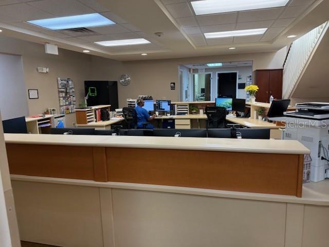 A reception area features a long wooden desk, office equipment, and a staff member working — 610 JASMINE ROAD, ALTAMONTE SPRINGS, FL