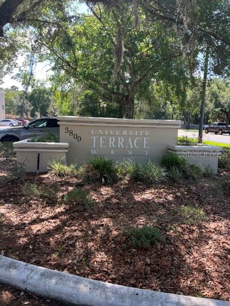 A beige monument sign for University Terrace West stands in a landscaped area with trees — 3800 SW 20TH AVENUE UNIT 204-Rm 4, GAINESVILLE, FL