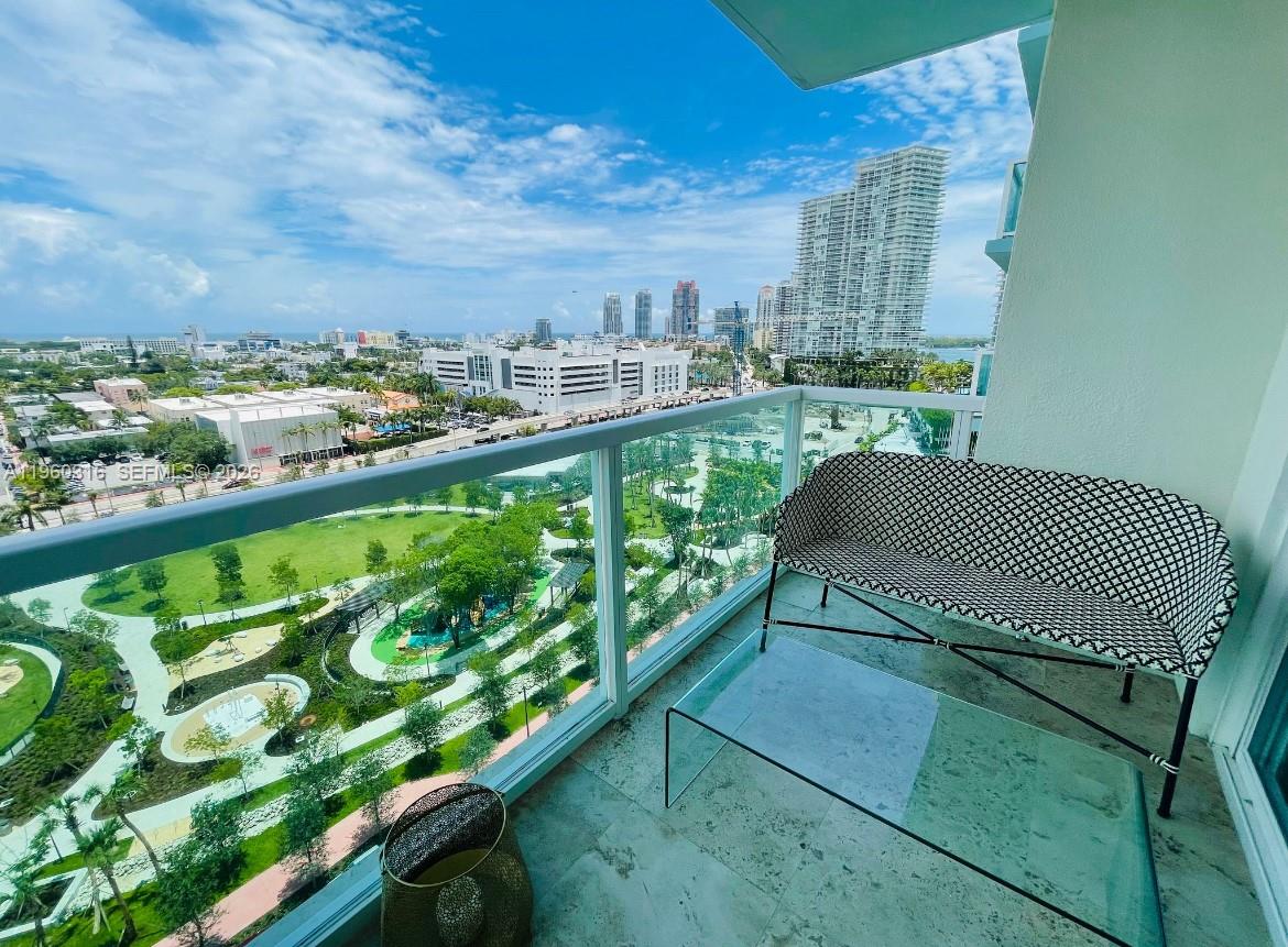 A balcony with a glass railing overlooks a park and city skyline under a blue sky — 650 West Ave # 1704, Miami Beach FL 33139, MIAMI BEACH, FL