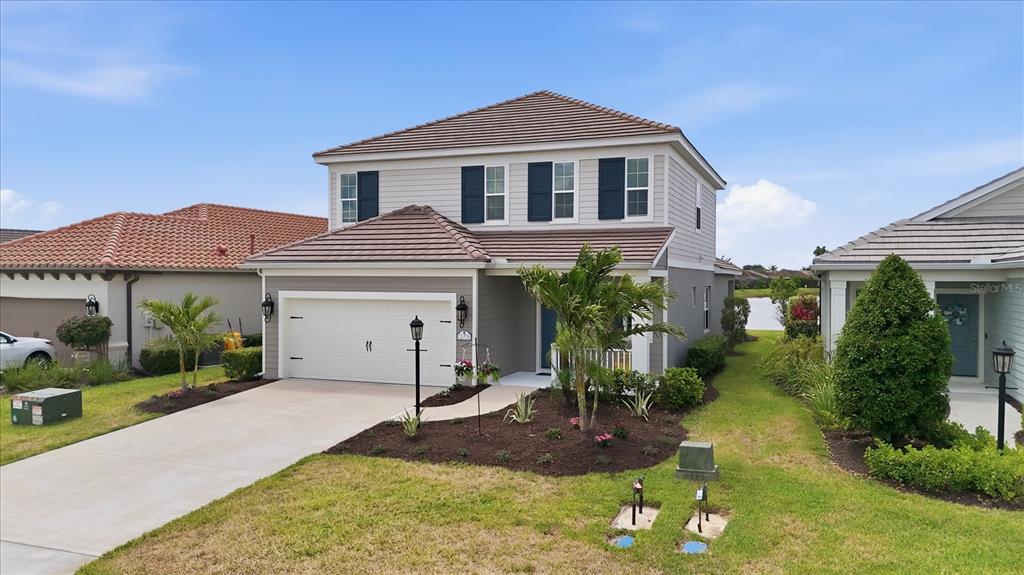 A two-story house with a white garage, gray siding, and a brown tiled roof — 12708 AQUAMARINE AVENUE, BRADENTON, FL