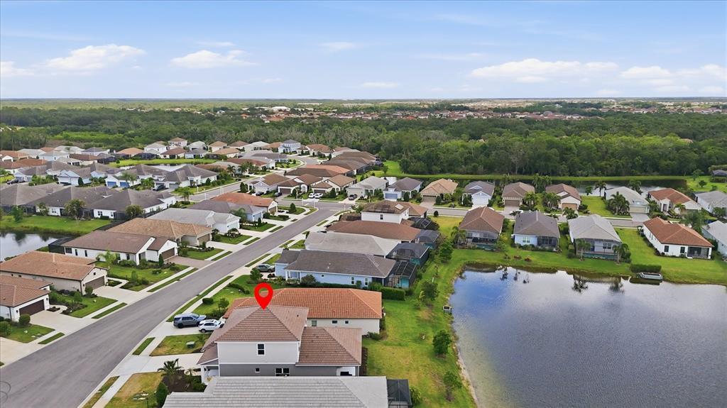 An aerial view shows a suburban neighborhood with houses surrounding a central pond — 12708 AQUAMARINE AVENUE, BRADENTON, FL