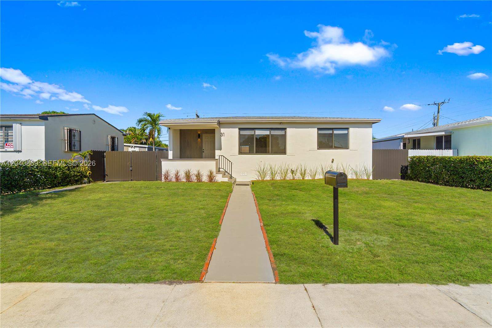 A single-story house with a white exterior, front lawn, and a sidewalk under a blue sky — 31 W 64th St, Hialeah FL 33012, HIALEAH, FL