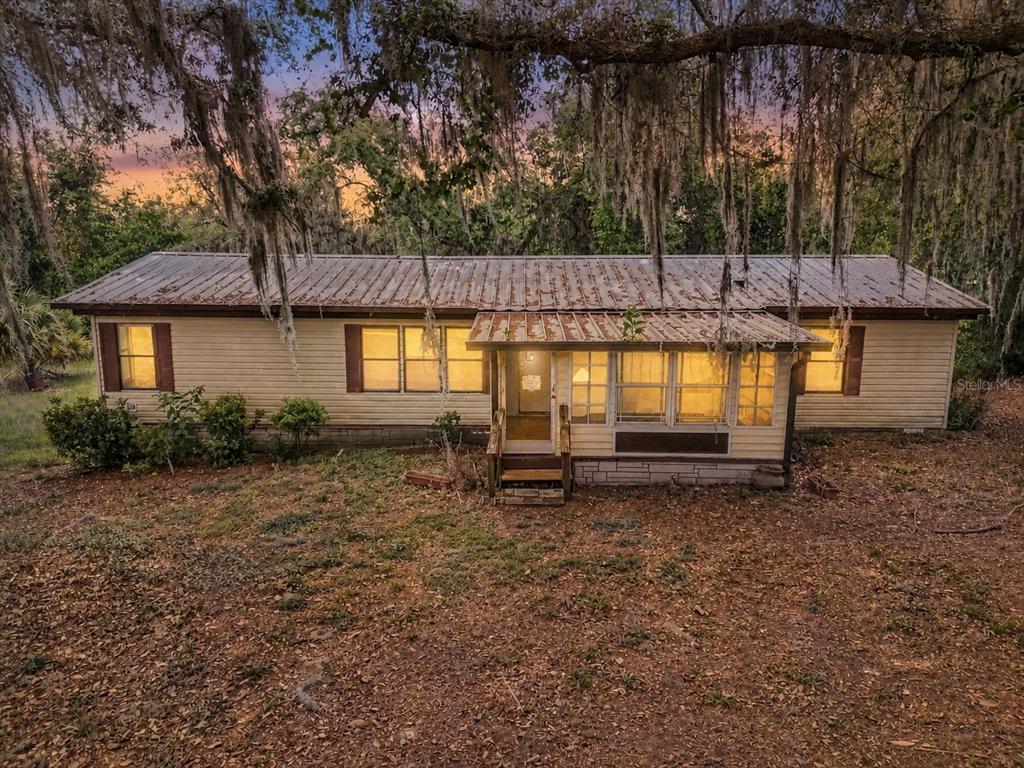 A single-story house with a rusted metal roof sits on a wooded lot — 18007 SE 90TH STREET, OCKLAWAHA, FL