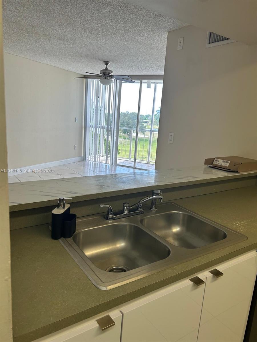 A kitchen sink with a countertop overlooks a living area with a balcony and view — 6955 NW 186th St # F505, Hialeah FL 33015, HIALEAH, FL
