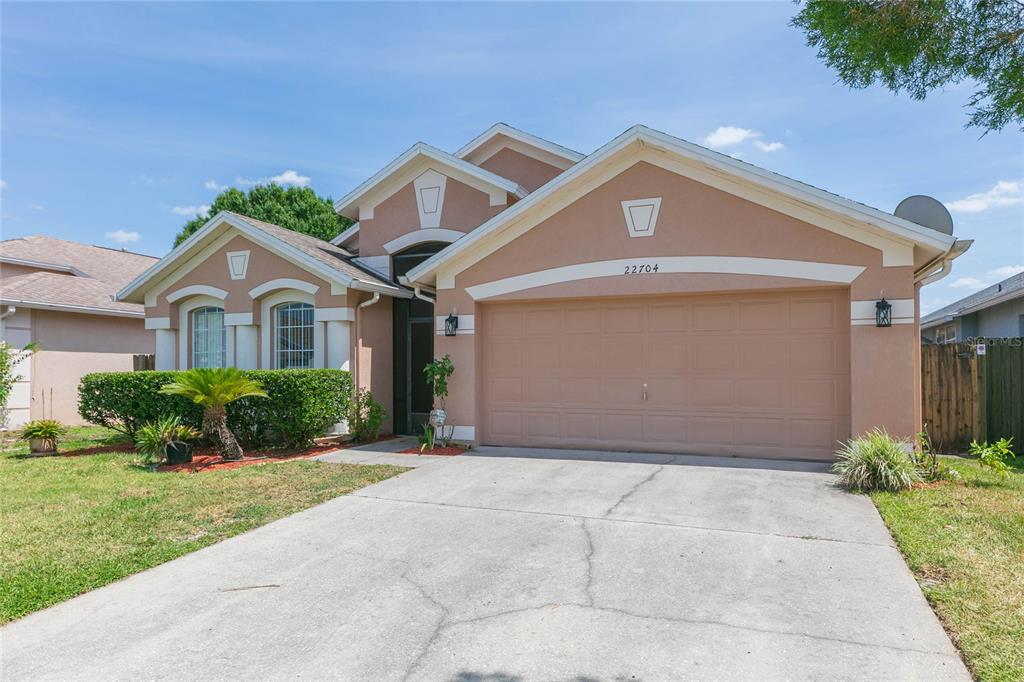 A single-story suburban house with a two-car garage, stucco exterior, and a concrete driveway — 22704 RODERICK DRIVE, LAND O LAKES, FL