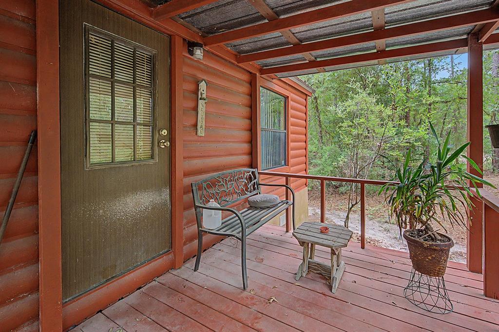 A wooden porch features a metal bench, a small side table, and a potted plant — 550 NW 73RD WAY, BELL, FL