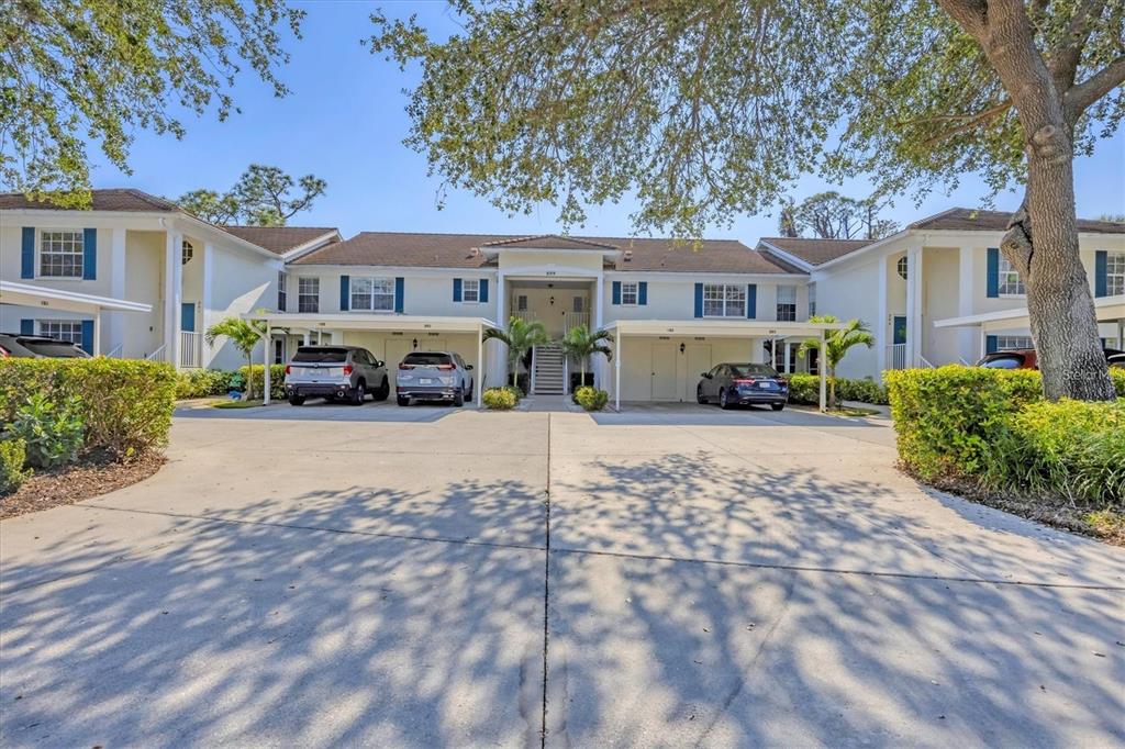 A two-story apartment building with covered parking spaces and a concrete driveway in front — 809 MONTROSE DRIVE UNIT 203, VENICE, FL