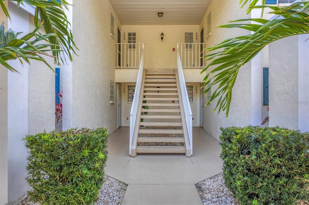 An exterior view of a two-story apartment building entrance with a central staircase — 809 MONTROSE DRIVE UNIT 203, VENICE, FL