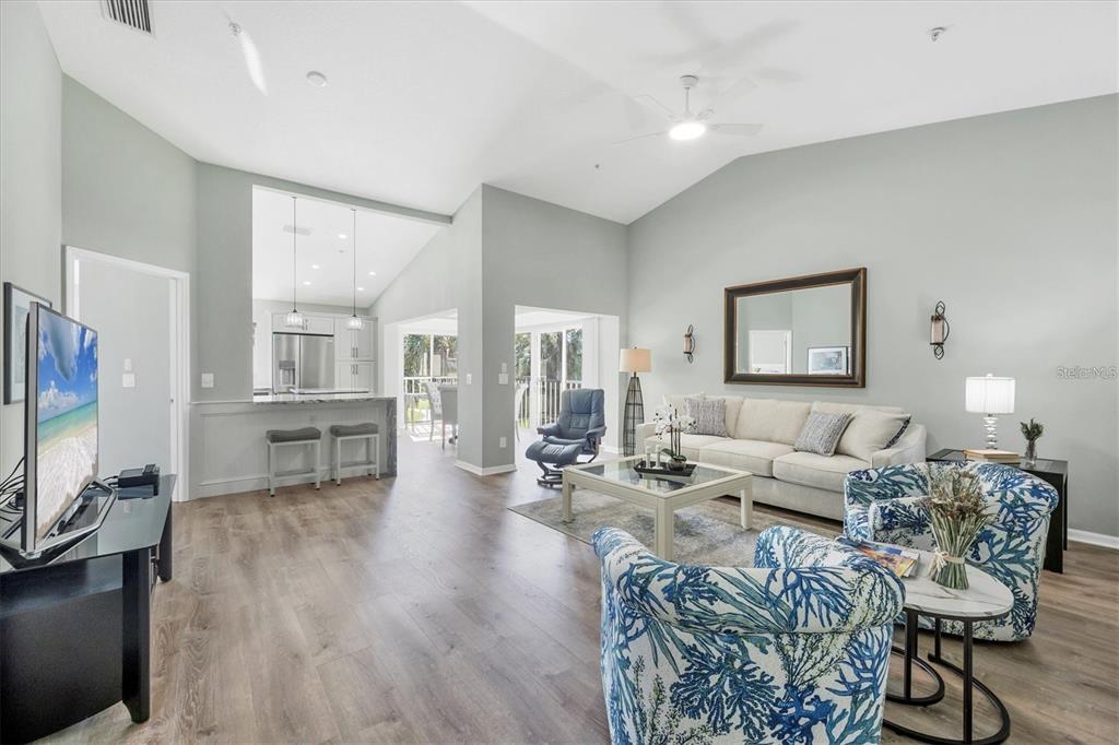 A living room with light gray walls, wood-look flooring, and a sofa with patterned armchairs — 809 MONTROSE DRIVE UNIT 203, VENICE, FL