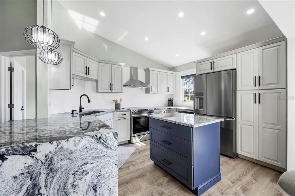 A kitchen features light gray cabinets, a blue island, and black-and-white granite countertops — 809 MONTROSE DRIVE UNIT 203, VENICE, FL