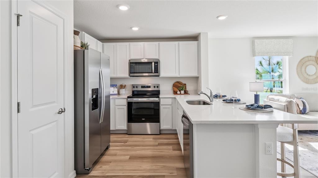 A modern kitchen features white cabinets, stainless steel appliances, and a quartz-topped island — 8304 GOWER TRAIL, WILDWOOD, FL