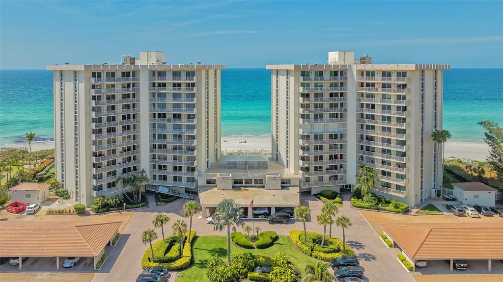 An aerial view shows two high-rise apartment buildings situated directly on a sandy beach — 2301 GULF OF MEXICO DRIVE UNIT 43N, LONGBOAT KEY, FL
