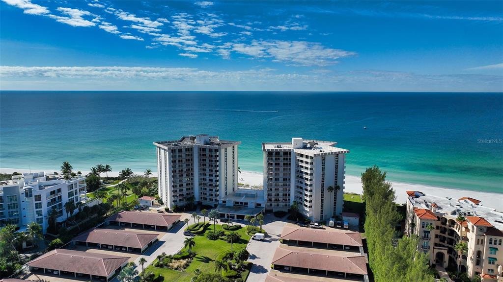 An aerial view shows two tall residential buildings situated on a sandy beach — 2301 GULF OF MEXICO DRIVE UNIT 43N, LONGBOAT KEY, FL