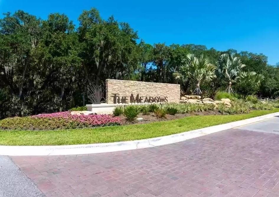 A stone monument sign reading The Meadows sits in a landscaped area with trees — 3107 HEATHERWOOD LANE, SARASOTA, FL
