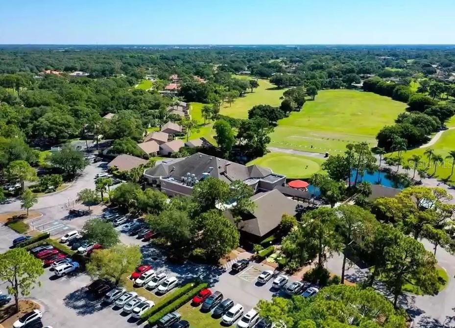 An aerial view shows a clubhouse building with a parking lot and a golf course — 3107 HEATHERWOOD LANE, SARASOTA, FL