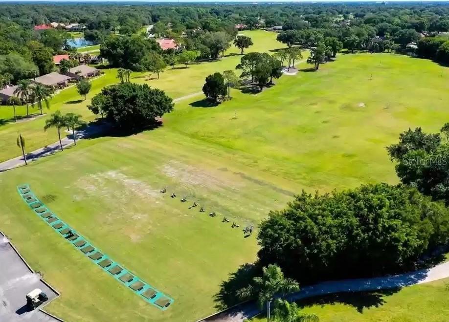 An aerial view of a golf course driving range with multiple hitting stations — 3107 HEATHERWOOD LANE, SARASOTA, FL