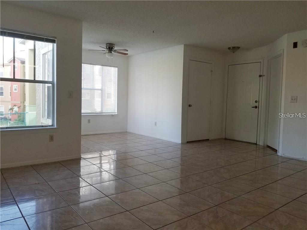 An empty room with tiled floors, a ceiling fan, and a white entry door — 2213 GRAND CAYMAN COURT UNIT 1128, KISSIMMEE, FL