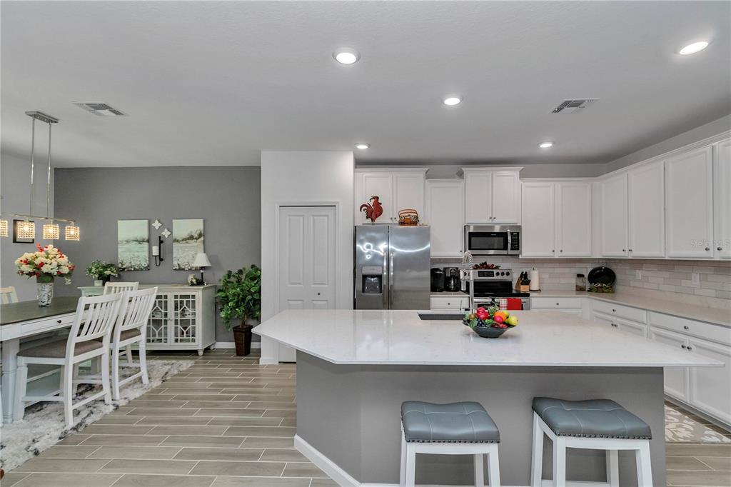 A living room features white leather furniture, a wooden entertainment center, and a tray ceiling — 7663 SW 74TH LOOP, OCALA, FL
