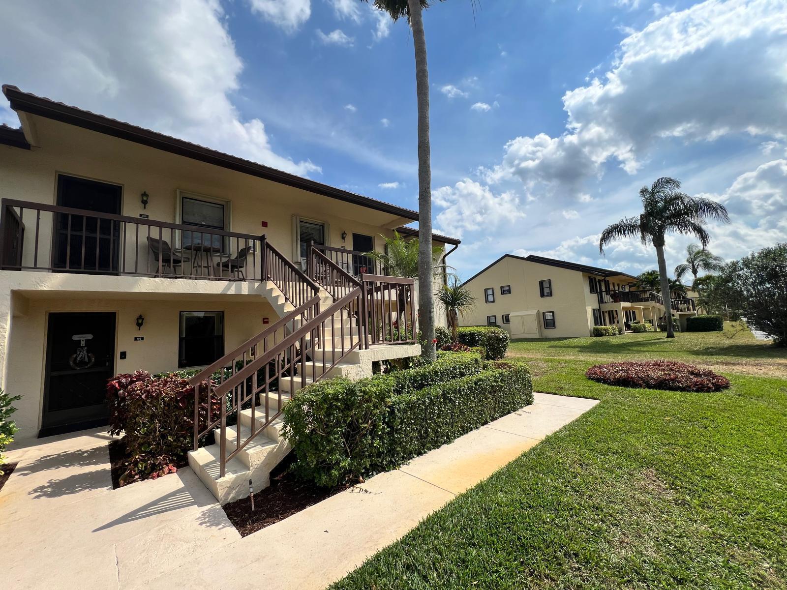 A two-story apartment building with exterior stairs, balconies, and palm trees on a sunny day — 4682 Lucerne Lakes Boulevard # 206, Lake Worth FL 33467, LAKE WORTH, FL