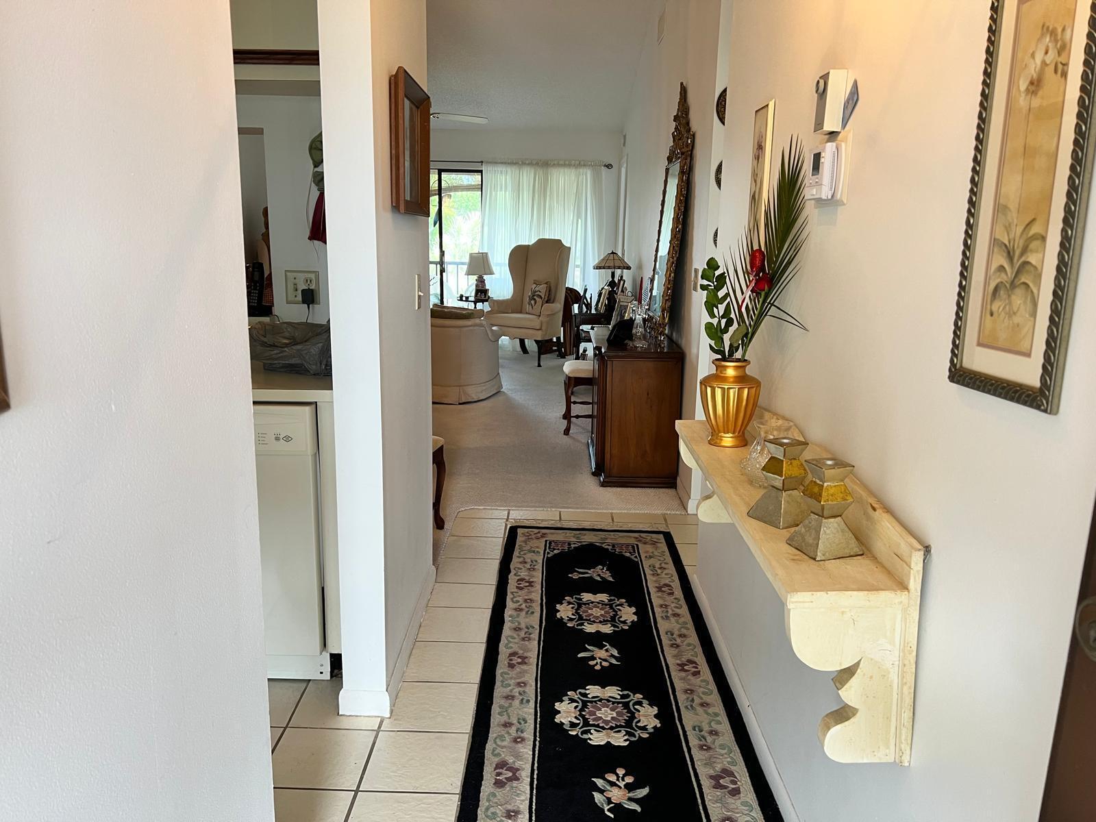 A tiled hallway with a runner rug leads toward a living room with carpeted floors — 4682 Lucerne Lakes Boulevard # 206, Lake Worth FL 33467, LAKE WORTH, FL