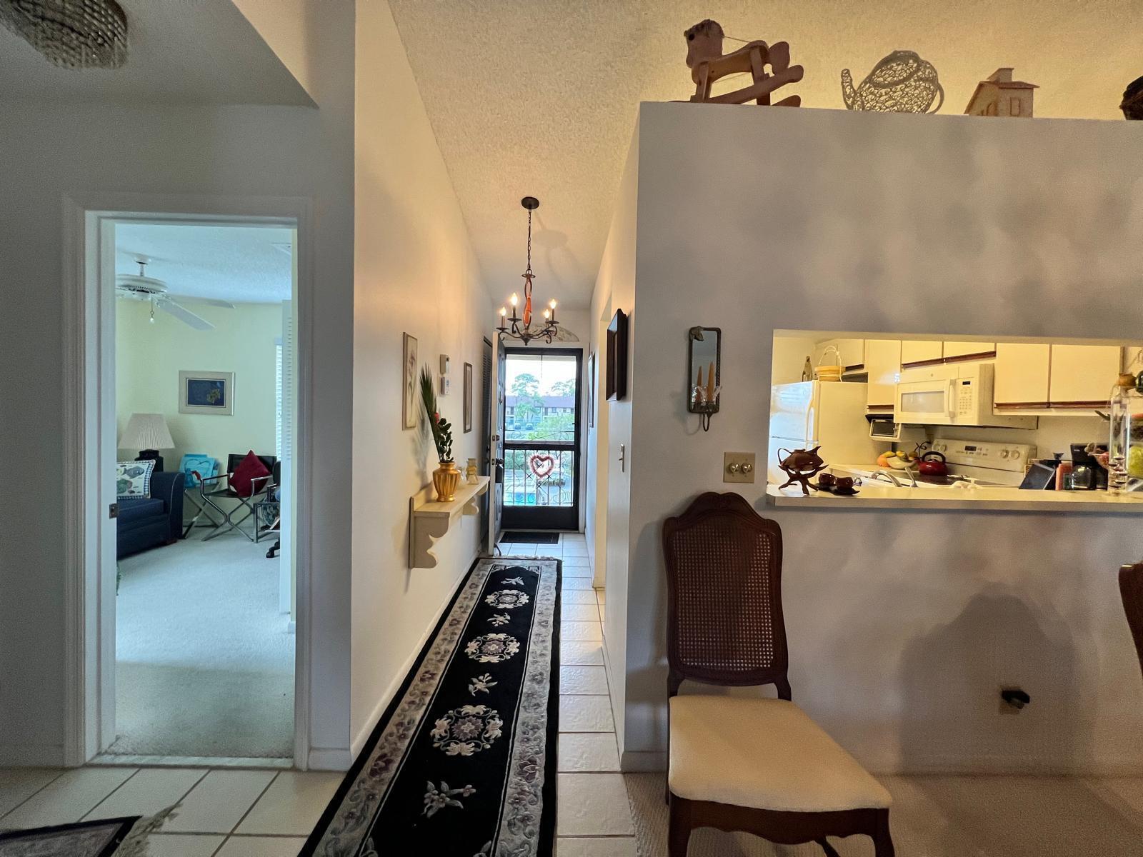 A tiled hallway leads to an entryway with a runner rug and a kitchen pass-through — 4682 Lucerne Lakes Boulevard # 206, Lake Worth FL 33467, LAKE WORTH, FL