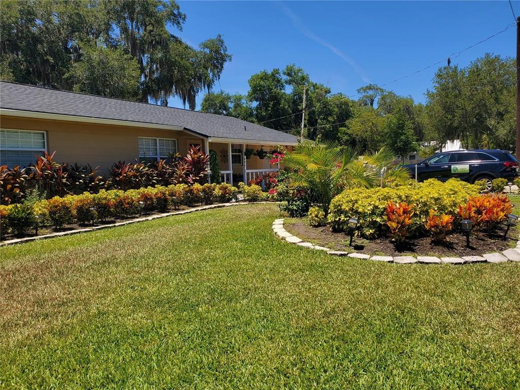 A single-story house with a tan exterior, dark roof, and landscaped front yard — 916 VERMONT AVENUE, ST CLOUD, FL