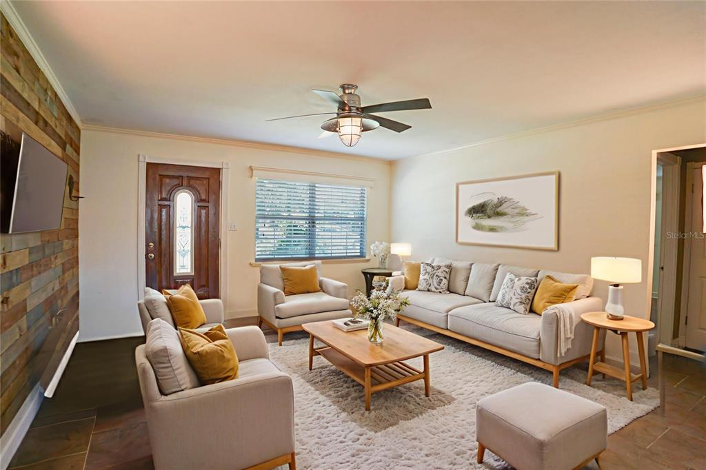 A living room features a wood-paneled accent wall, neutral furniture, and a ceiling fan — 916 VERMONT AVENUE, ST CLOUD, FL