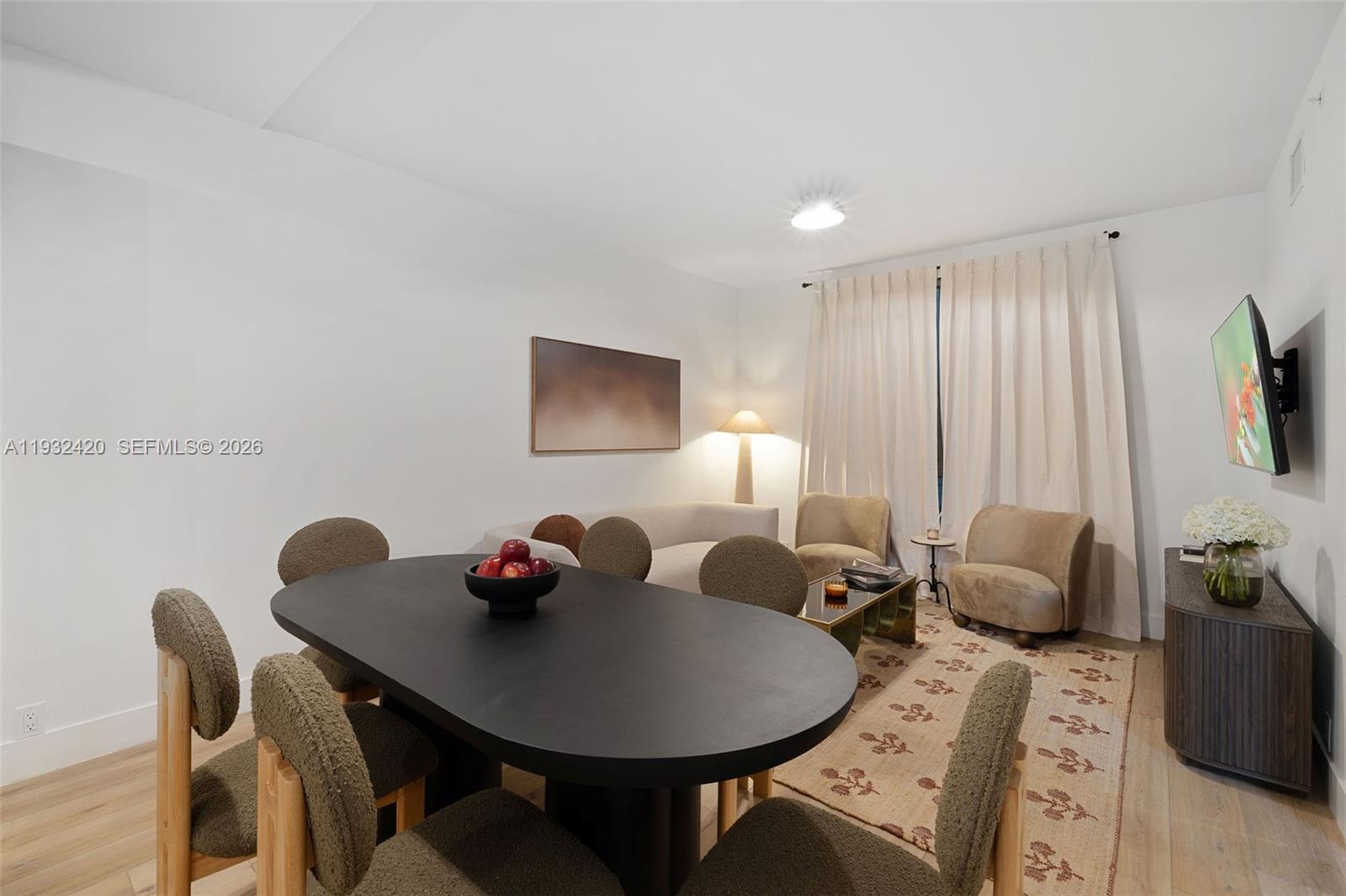 This open-concept living and dining area features modern light fixtures, wood flooring, and neutral furniture — 1542 NW 2nd St # 105, Miami FL 33125, MIAMI, FL