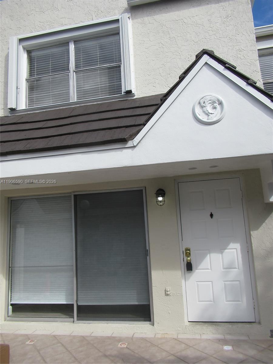 A white exterior wall features a sliding glass door, a front door, and a window — 6825 SW 45th Ln # 12, Miami FL 33155, MIAMI, FL