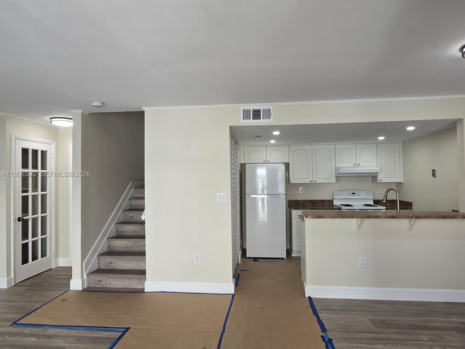 A kitchen with white cabinets and a refrigerator sits next to a staircase — 6825 SW 45th Ln # 12, Miami FL 33155, MIAMI, FL