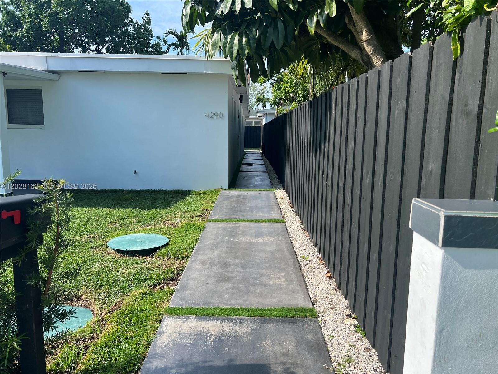 A concrete walkway leads along the side of a white house next to a black fence — 4290 SW 9th St # B, Miami FL 33134, MIAMI, FL