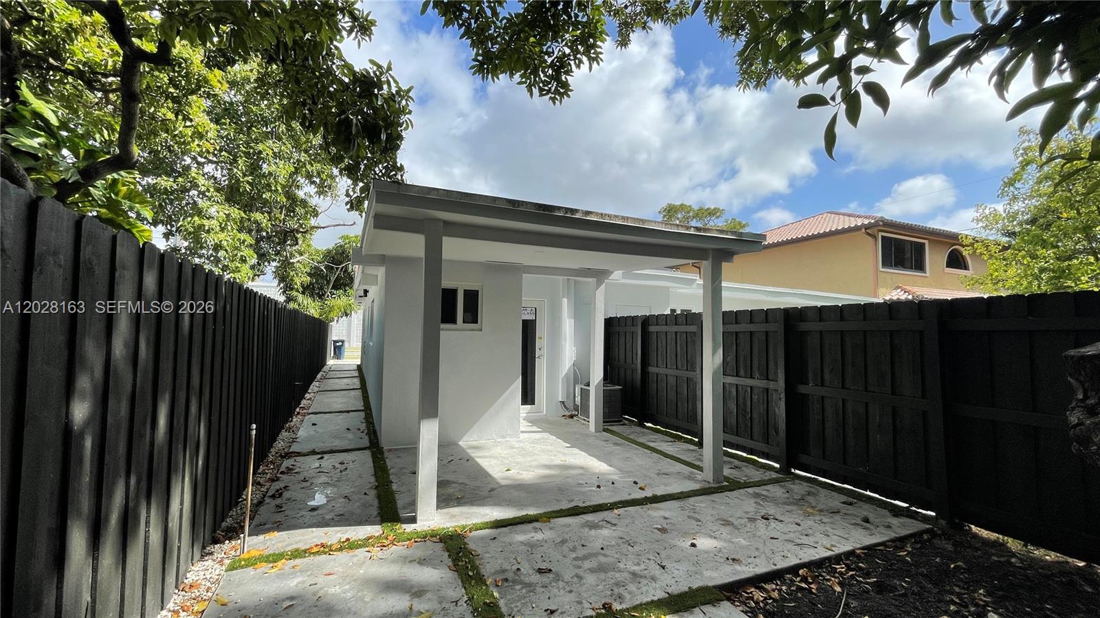 A small white structure with a covered patio sits between two black wooden fences — 4290 SW 9th St # B, Miami FL 33134, MIAMI, FL