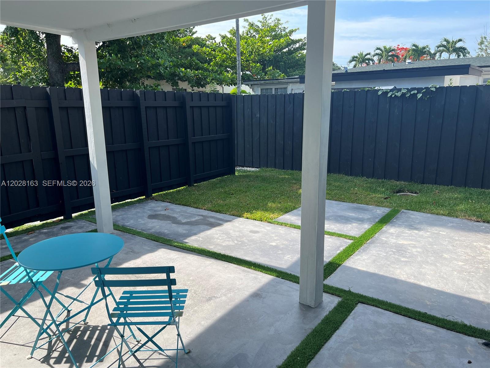A patio features a blue bistro set, concrete pavers with grass strips, and a black fence — 4290 SW 9th St # B, Miami FL 33134, MIAMI, FL