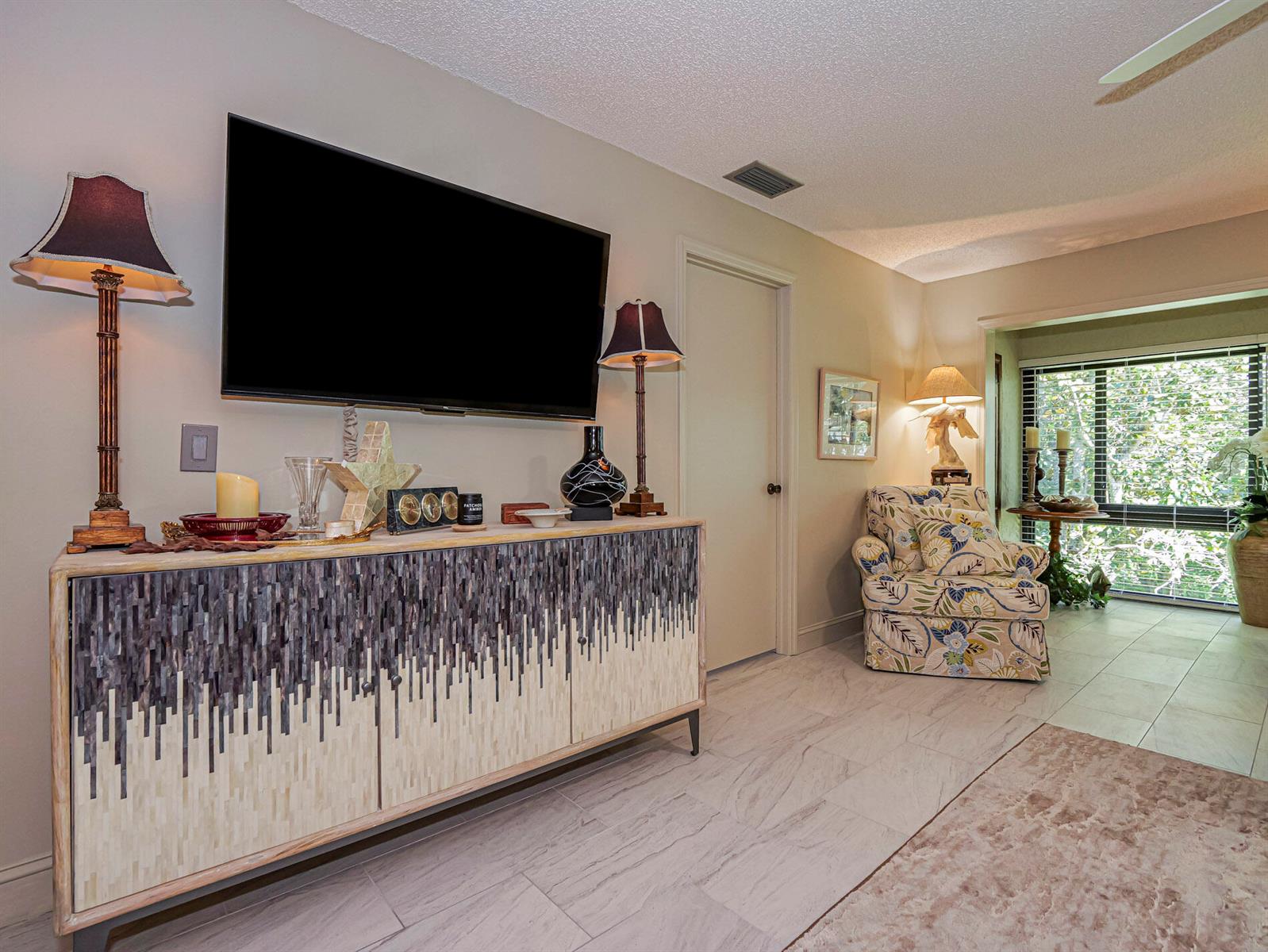 A living room features a textured console table, a wall-mounted television, and a patterned armchair — 400 18th Street # G5, Vero Beach FL 32960, VERO BEACH, FL