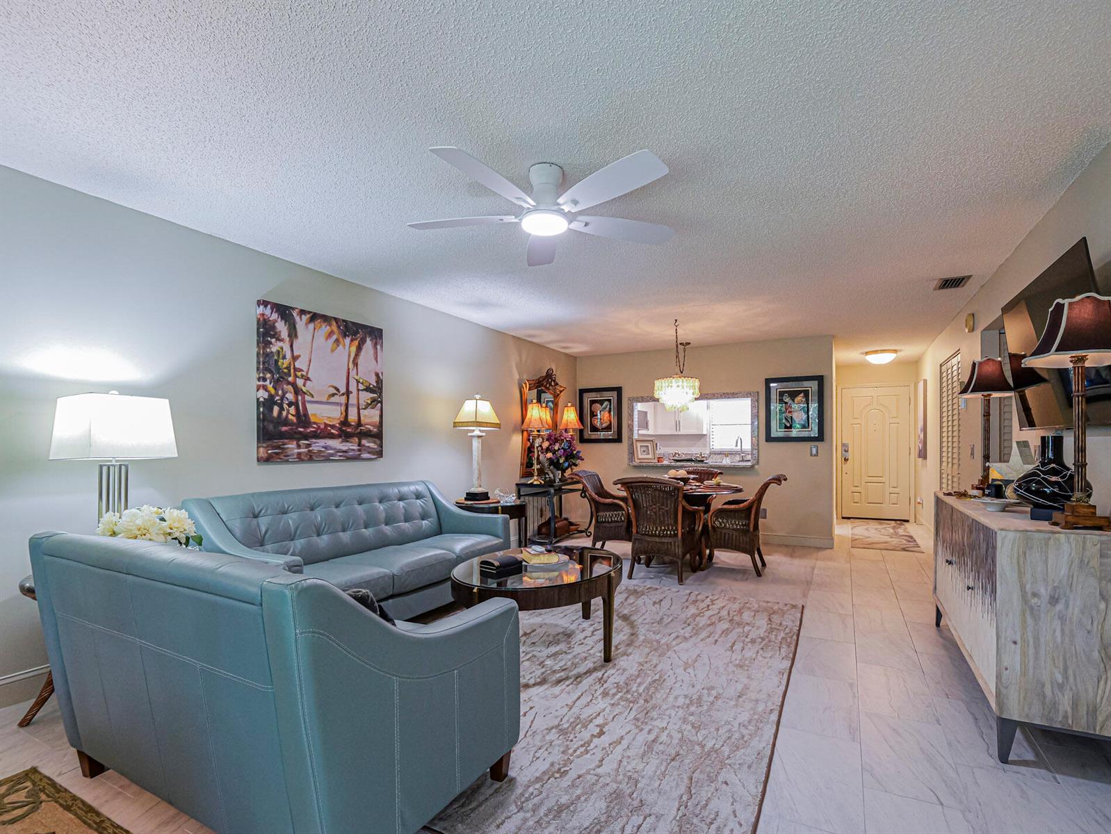 A living room with a blue sofa, dining area, and tiled floors leads to an entryway — 400 18th Street # G5, Vero Beach FL 32960, VERO BEACH, FL