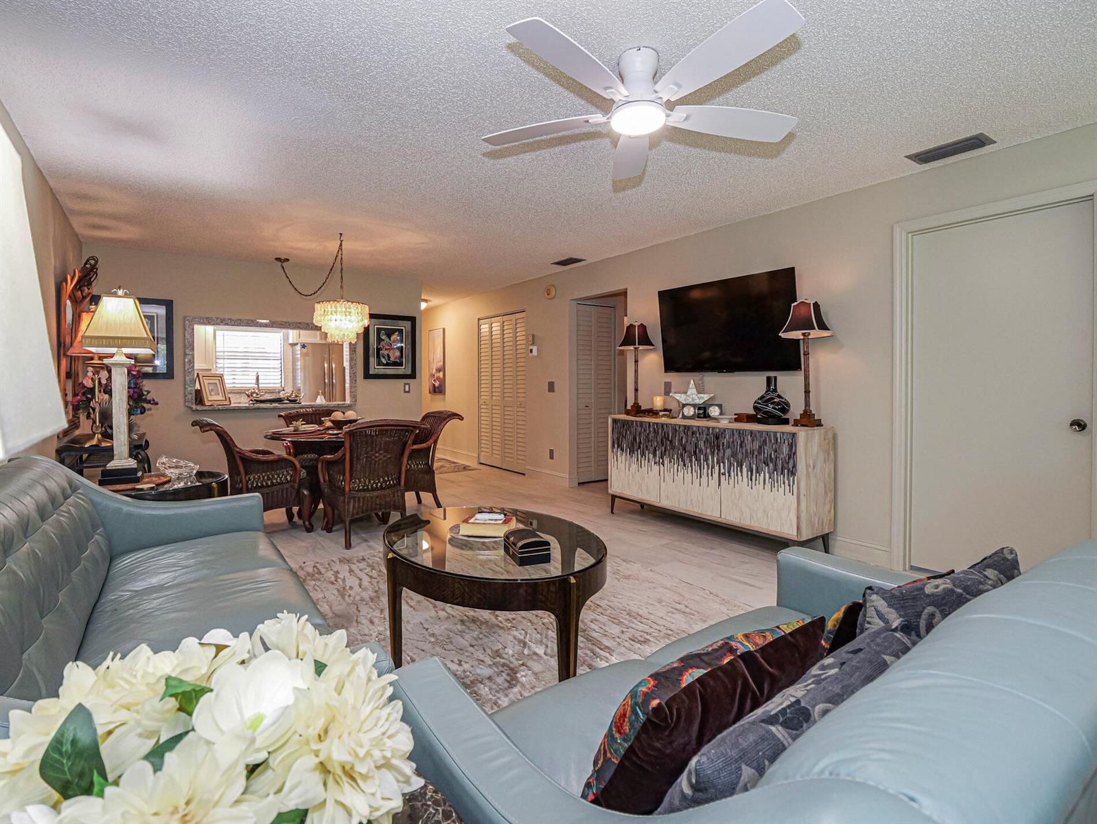 A living room with light blue leather sofas, a glass coffee table, and a dining area — 400 18th Street # G5, Vero Beach FL 32960, VERO BEACH, FL