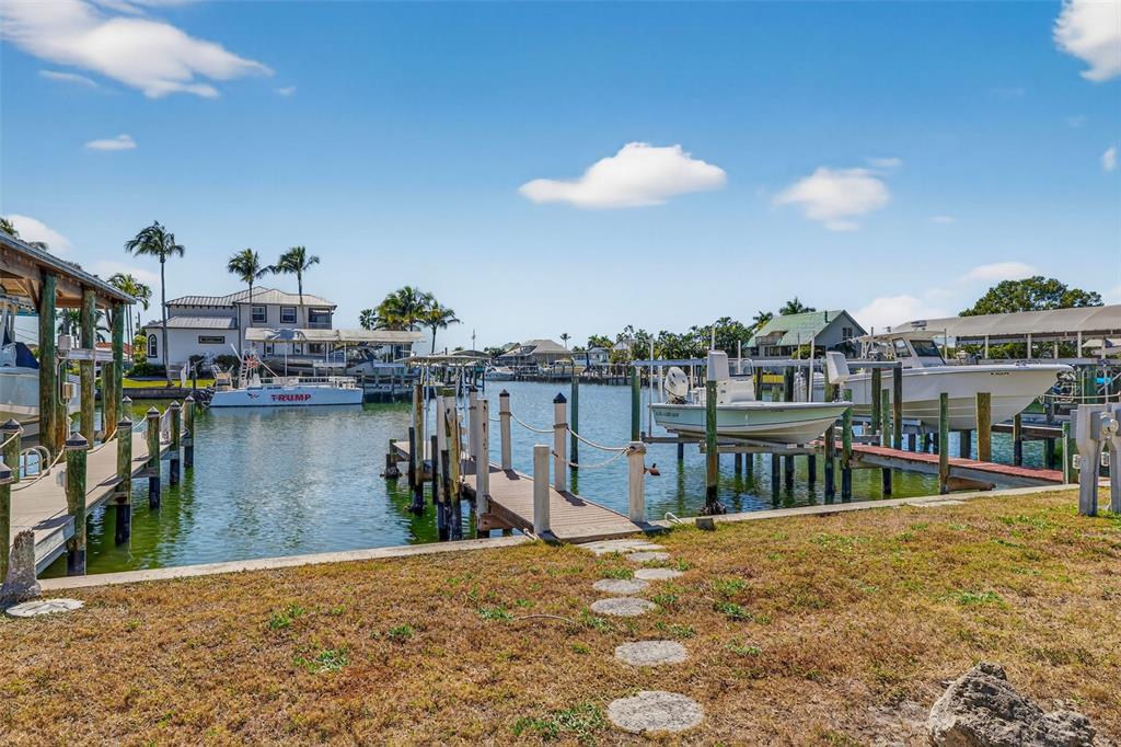 A canal view featuring wooden boat docks, a boat lift, and several docked motorboats — 12130 SIESTA DRIVE, FORT MYERS BEACH, FL